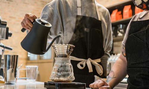 barista making pour over coffee in coffee shop